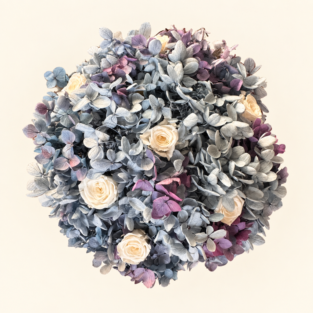 Brezza Marina vista dall’alto: bouquet intero di ortensie azzurre e malva con rose avorio su fondo chiaro.