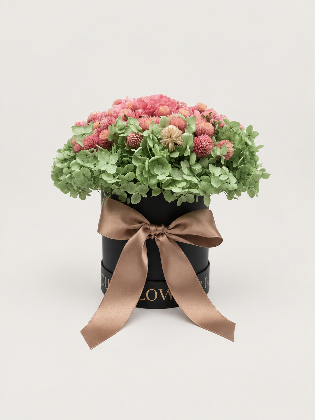 Giardino di Seta: ortensie verde salvia e rosa cipria stabilizzate in cappelliera nera con fiocco satinato caramello.
