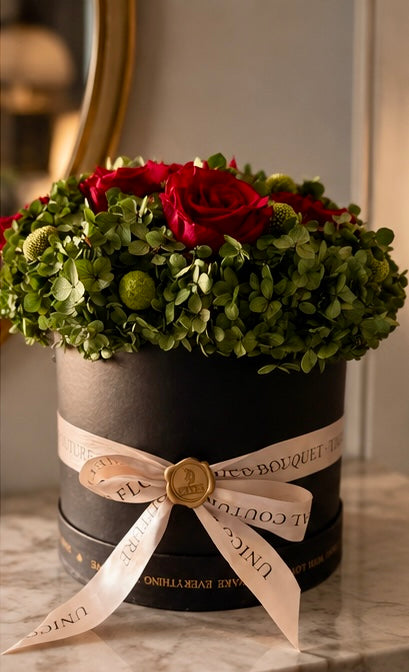 Foto originale di Rosso Bosco: bouquet di rose rosse e ortensie verdi in vaso nero, nastro UNICO Bouquet champagne e sigillo dorato.