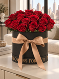 Rosso Imperiale: ventuno rose rosse stabilizzate in cappelliera nera con fiocco champagne, davanti a una vetrata su New York.