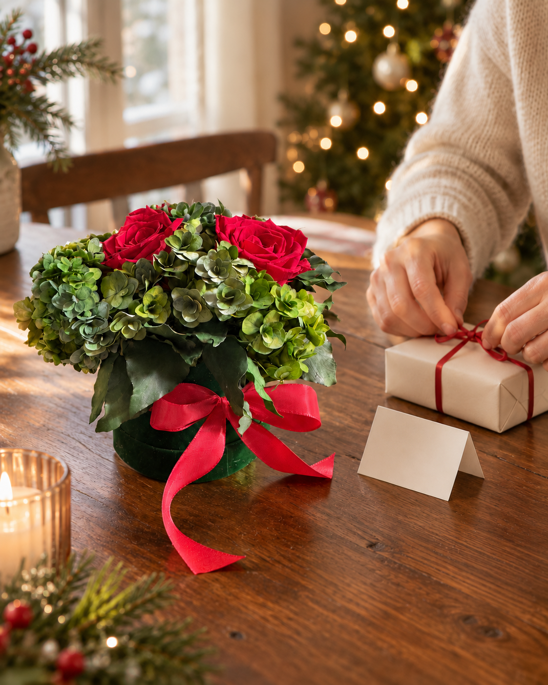 Bouquet con rose rosse e ortensie verdi, fiocco rosso e mani che preparano un regalo di Natale